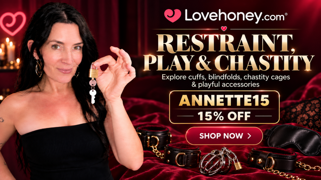 Annette benedetti in black holding a male chastity cock cage key and products from Lovehoney.com on a red bed text reading 15% off with code ANNETTE15